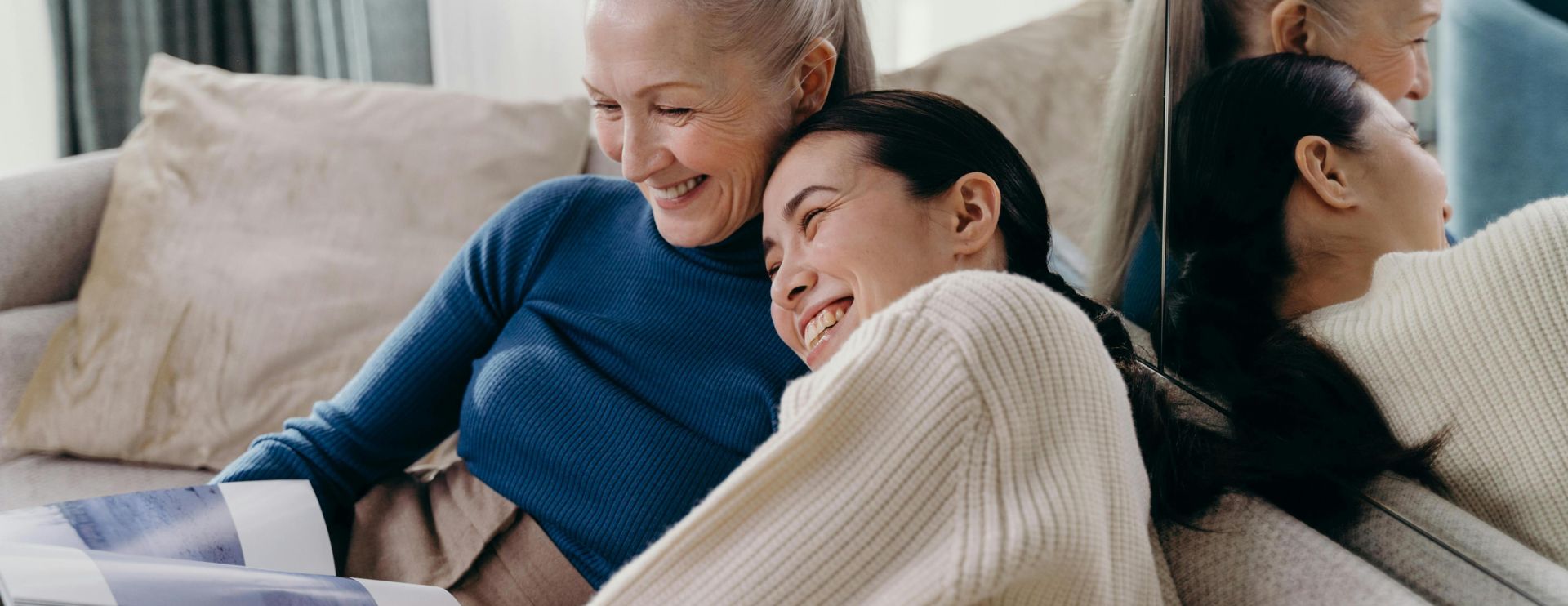 A joyful moment between a mother and daughter embracing each other on a sofa at home.